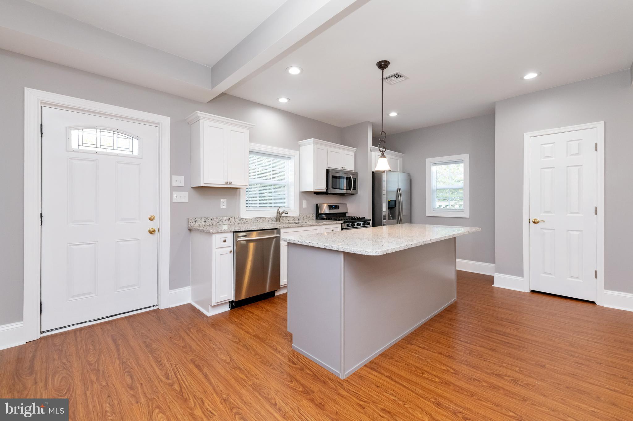 2505 Hammonds Ferry Road Baltimore, MD 21227 - Photo 10 of 36 a large kitchen with a center island wooden floor stainless steel appliances and a window