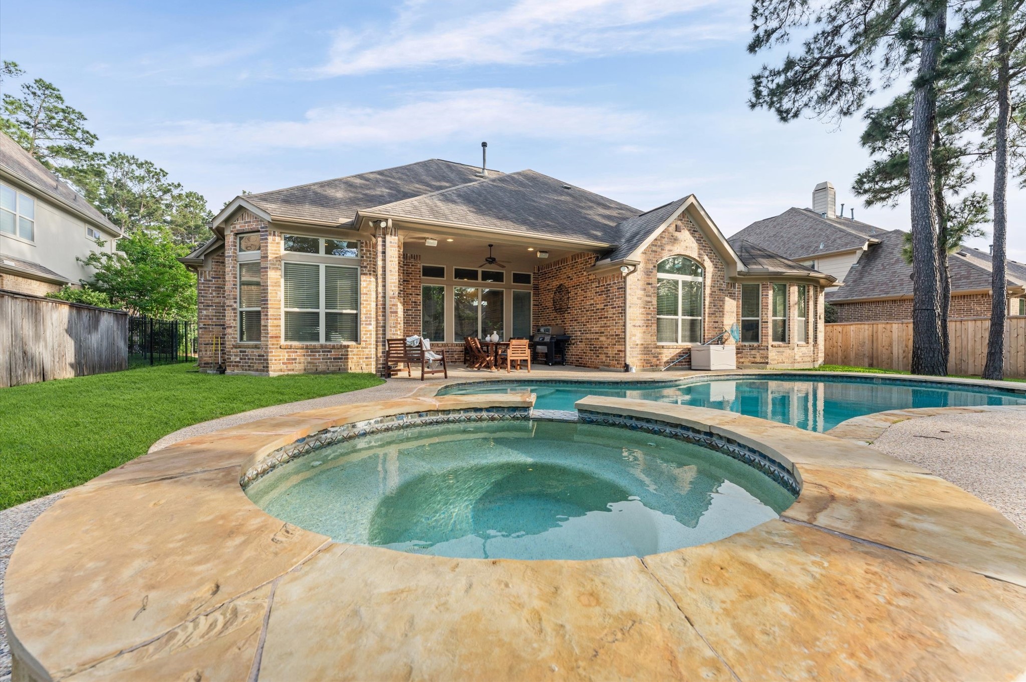 70 Valera Ridge Drive Spring, TX 77389 - Photo 6 of 37 This is a charming brick home featuring a spacious backyard with a covered patio, pool, and spa, surrounded by lush greenery and mature trees, offering a private oasis for relaxation and entertainment.