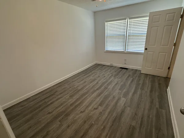 a view of an empty room with wooden floor and closet