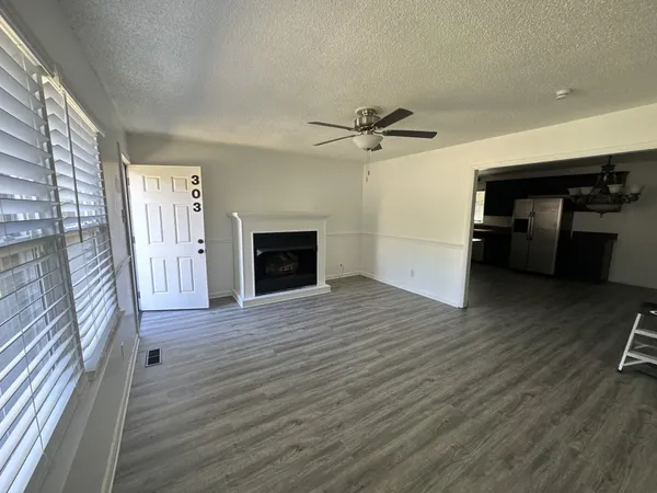 a view of a livingroom with a fireplace a ceiling fan and wooden floor