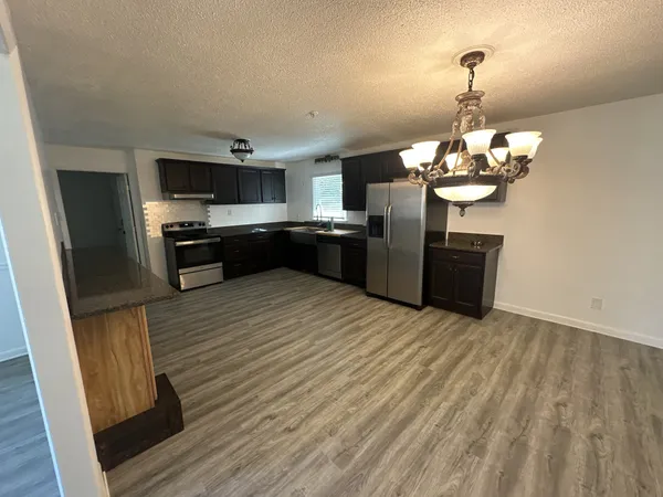 a kitchen with stainless steel appliances granite countertop a sink a stove a refrigerator with grey cabinets and wooden floor