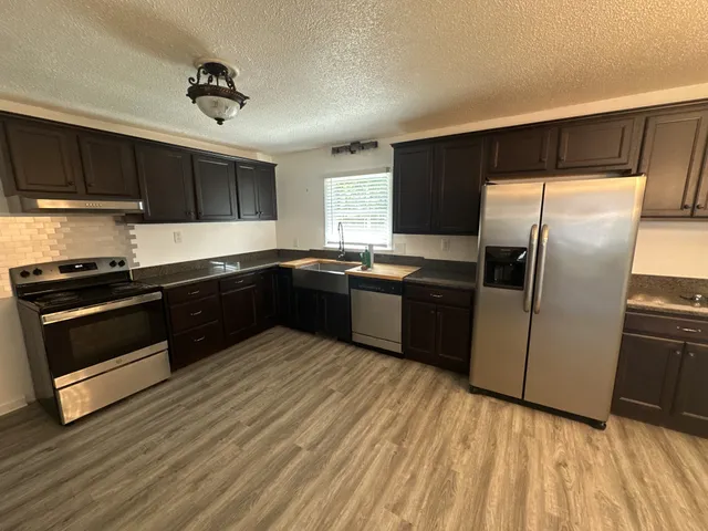 a view of a kitchen with wooden floor and electronic appliances