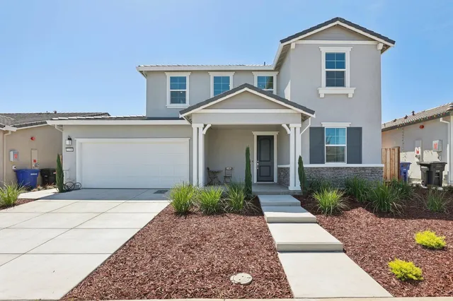 a front view of a house with a yard and potted plants