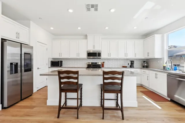 a kitchen with stainless steel appliances granite countertop a stove a sink a refrigerator and white cabinets