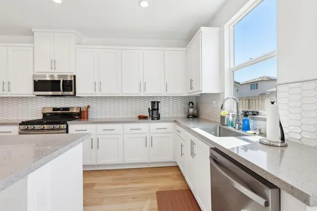 a kitchen with stainless steel appliances granite countertop a sink a stove and cabinets