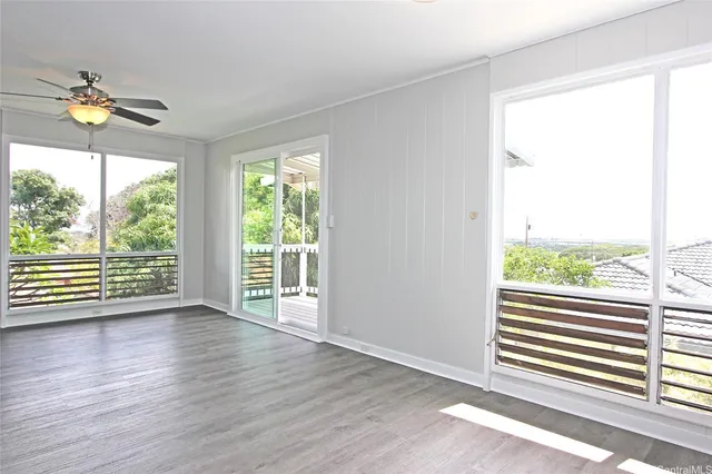 a view of empty room with wooden floor and fan