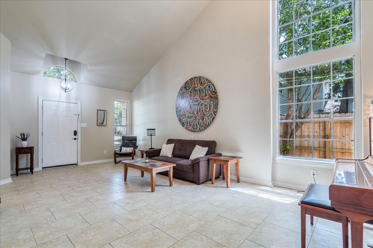 9300 Tea Rose Trail Austin, TX 78748 - Photo 9 of 33 Natural light fills this inviting living space through a grand window, complemented by vaulted ceilings.