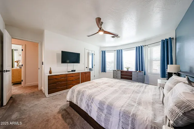a bedroom with a large bed a flat tv screen and a chandelier