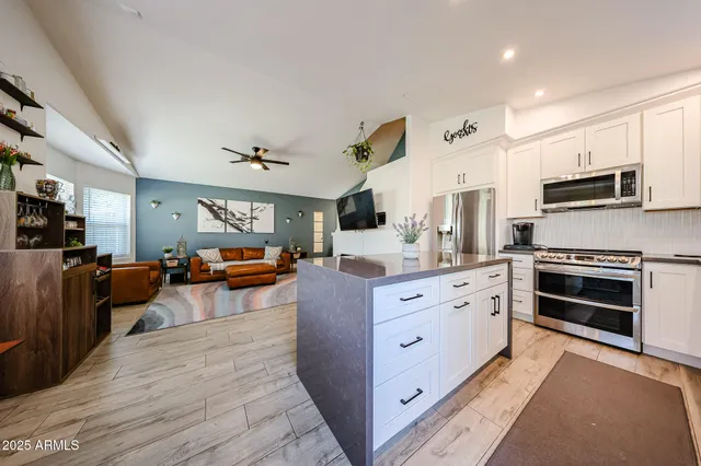 a kitchen with stainless steel appliances kitchen island granite countertop a stove top oven a sink dishwasher a dining table and chairs with wooden floor