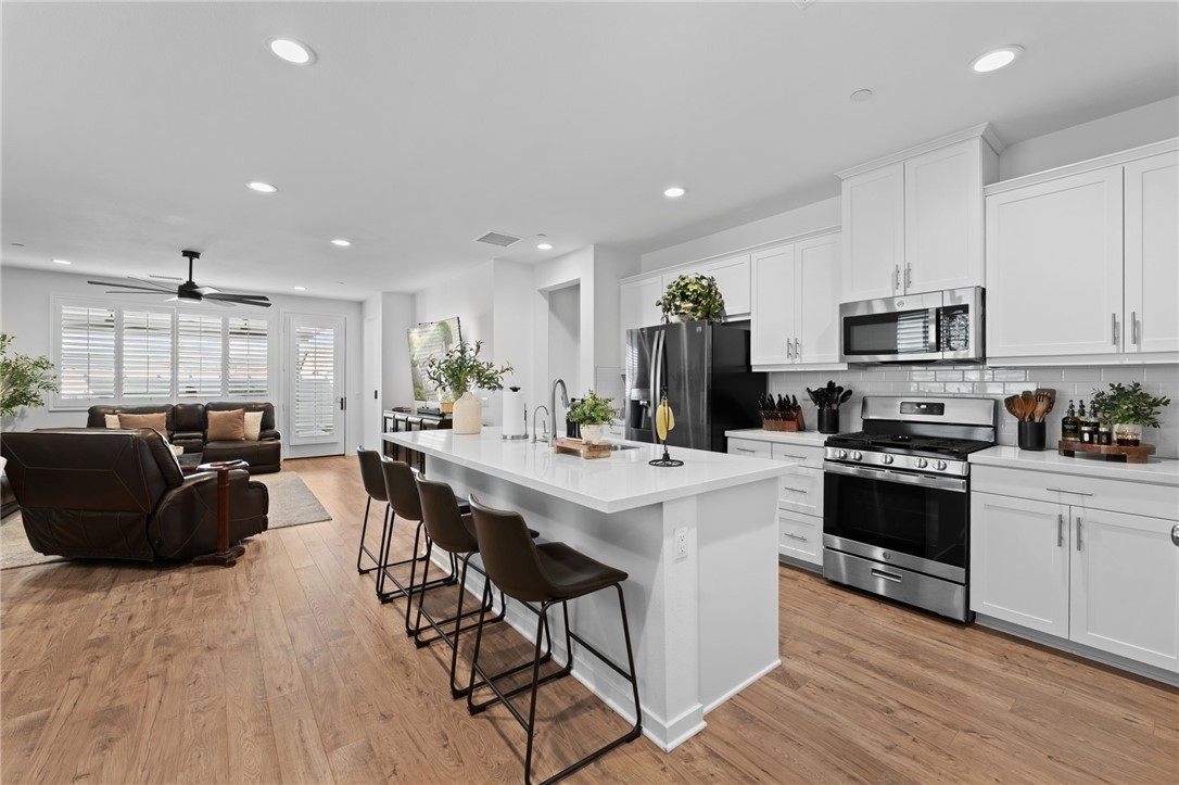36938 Frantoio Street Beaumont, CA 92223 - Photo 17 of 35 a kitchen with stainless steel appliances kitchen island granite countertop a stove a sink a refrigerator and white cabinets with wooden floor