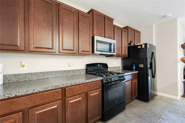 a kitchen with granite countertop wooden cabinets a stove a sink and dishwasher