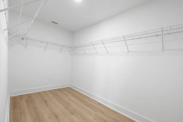 an empty room with wooden floor closet and windows