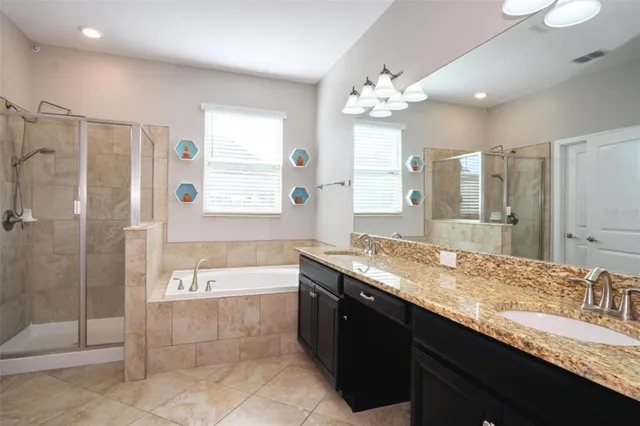a spacious bathroom with a granite countertop double vanity sink mirror bathtub and shower