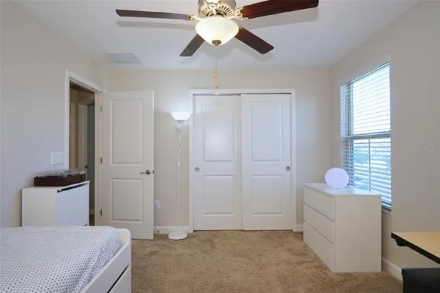 a bedroom with a chandelier fan and a window