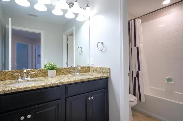 a bathroom with a granite countertop sink a mirror and a shower
