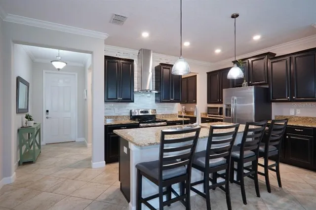 a kitchen with stainless steel appliances kitchen island granite countertop a table chairs and a refrigerator