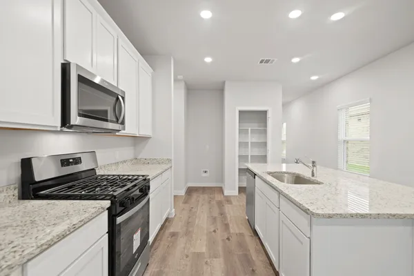 a kitchen with stainless steel appliances granite countertop a sink stove and microwave