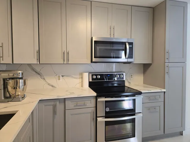 a kitchen with granite countertop white cabinets and stainless steel appliances
