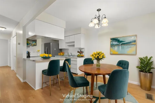 a kitchen with stainless steel appliances granite countertop a dining table chairs and a refrigerator