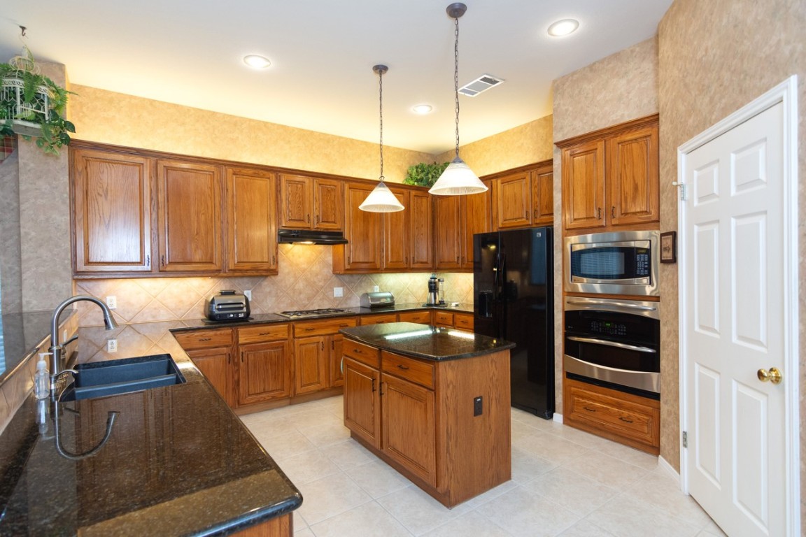 11401 Ohmfield Court Austin, TX 78739 - Photo 12 of 40 a kitchen with stainless steel appliances granite countertop a refrigerator a sink and wooden cabinets
