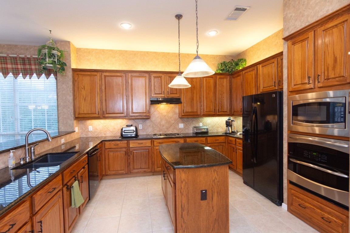 11401 Ohmfield Court Austin, TX 78739 - Photo 13 of 40 a kitchen with stainless steel appliances granite countertop a sink a stove and a refrigerator