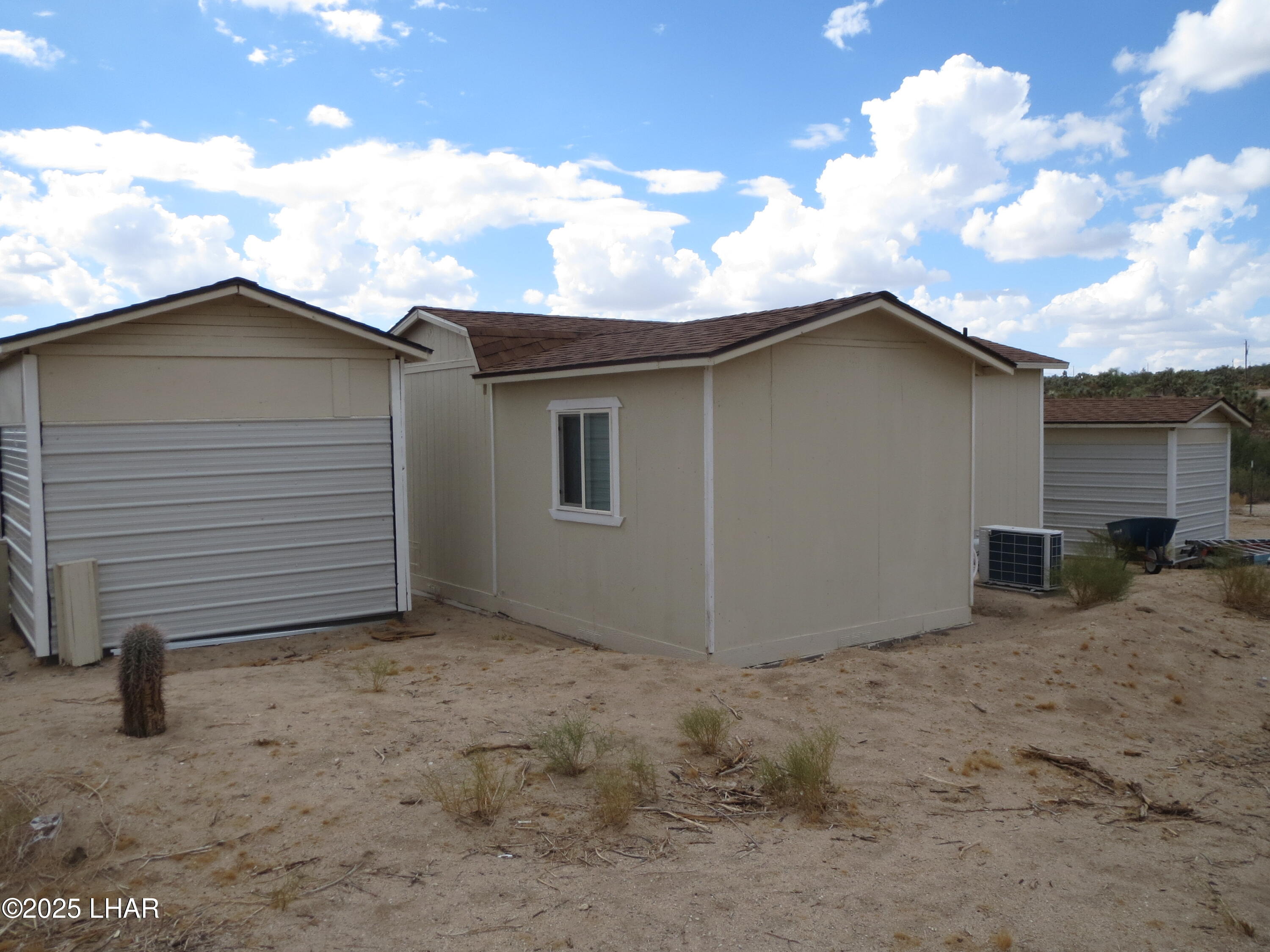 11964 Nolan Road Yucca, AZ 86438 - Photo 27 of 29 Rear view of storage sheds, water storage building and house.