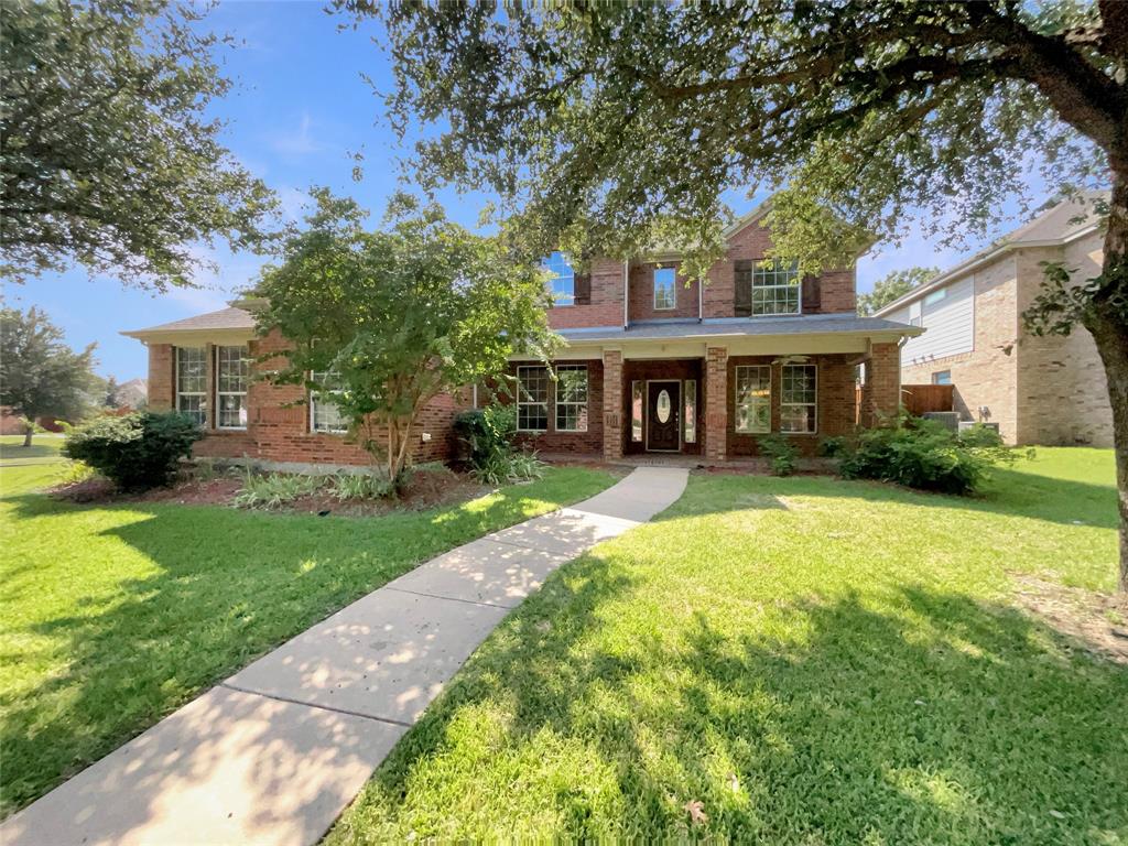 Traditional home featuring brick siding, a front yard, and covered porch