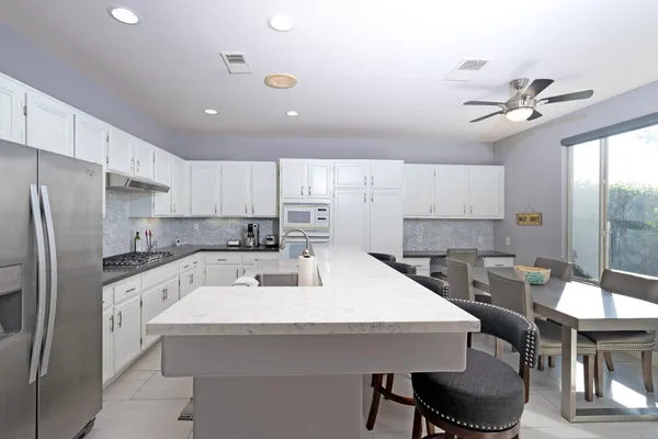 a kitchen with stainless steel appliances a white table chairs and a refrigerator