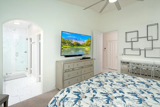 a bedroom with a bed and a flat screen tv in a white room
