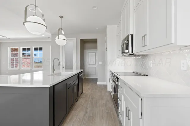 a kitchen with kitchen island granite countertop a sink a counter space and stainless steel appliances