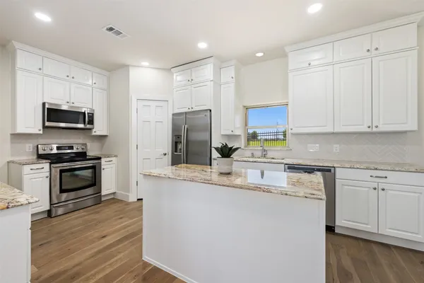 a kitchen with kitchen island granite countertop a stove a sink and a refrigerator