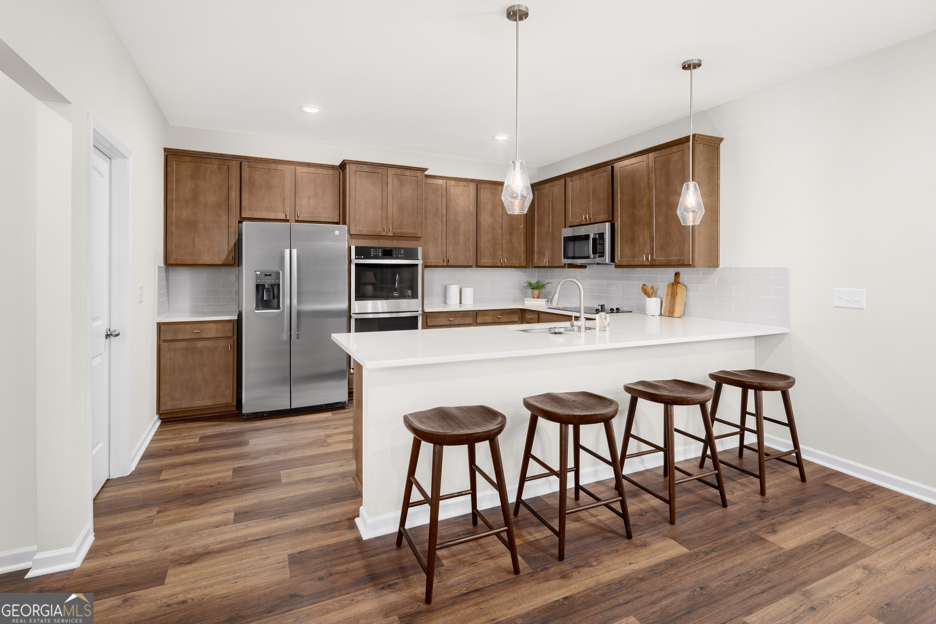 129 Southeast Honey Creek Road, Unit 4 Conyers, GA 30094 - Photo 16 of 21 a kitchen with stainless steel appliances granite countertop a refrigerator a sink dishwasher a stove and white cabinets with wooden floor