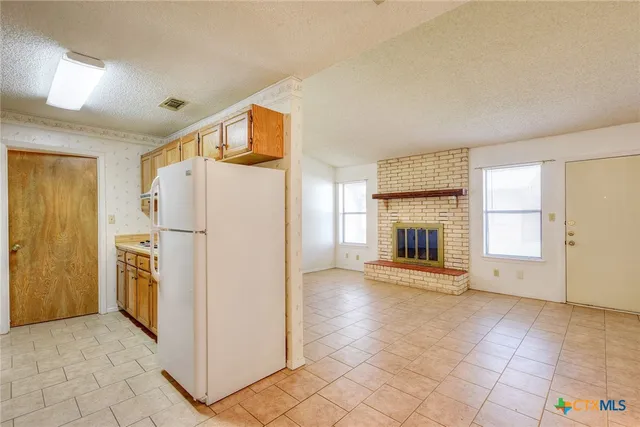a view of a kitchen with refrigerator and an empty room