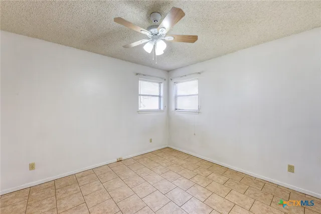 an empty room with windows and ceiling fan