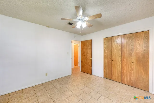 a view of an empty room and chandelier fan
