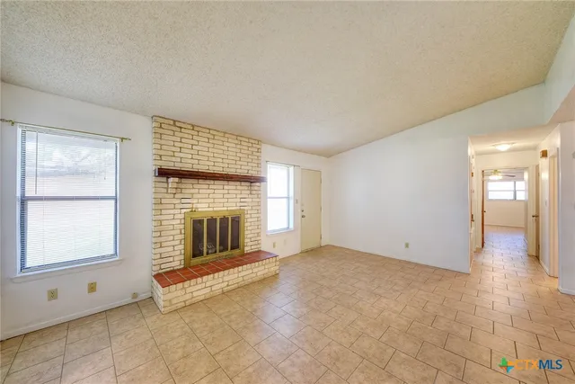 a view of an empty room with a fireplace and a window