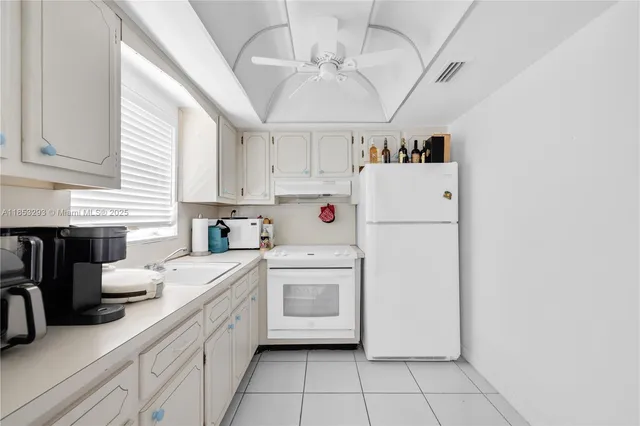 a kitchen with cabinets a sink and white appliances