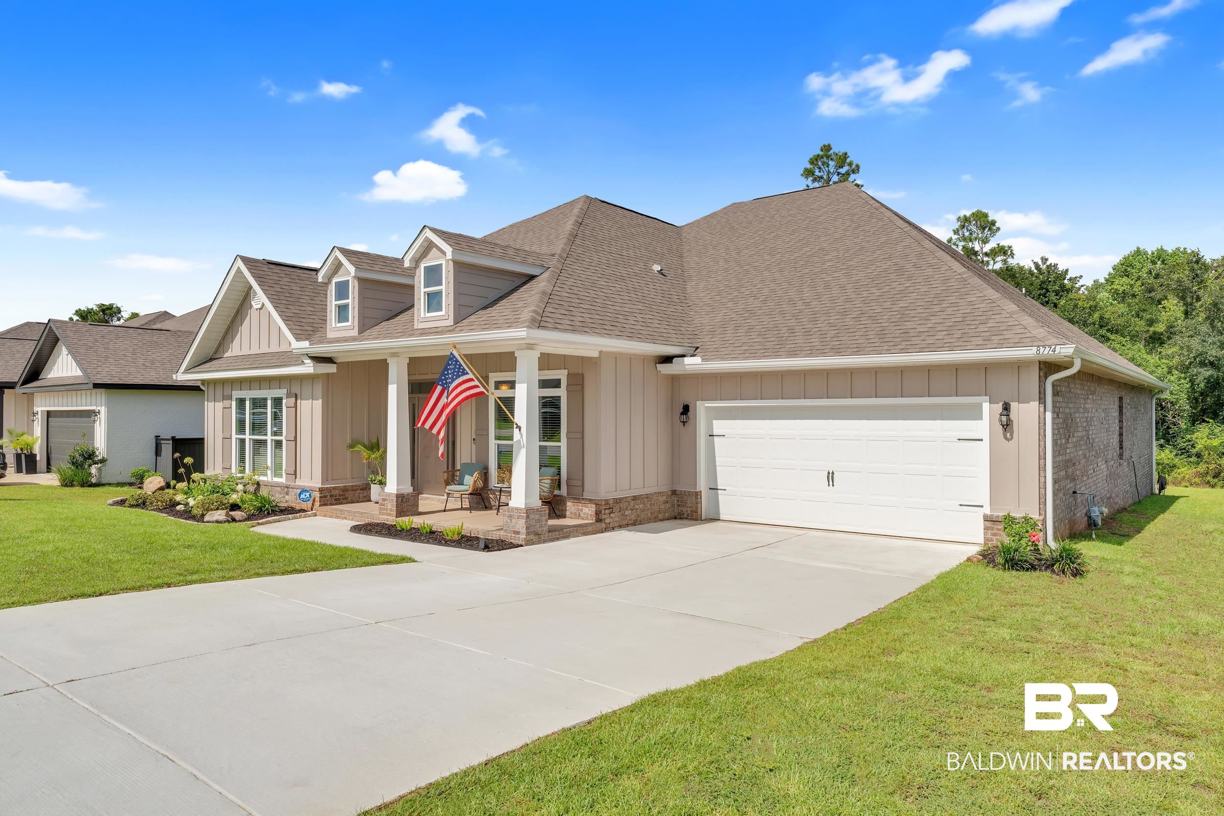 8774 Primland Boulevard Foley, AL 36535 - Photo 2 of 49 View of front of property with a porch, roof with shingles, board and batten siding, a front lawn, and a garage