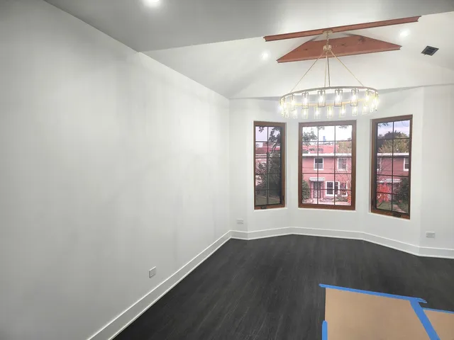 en empty room with a window and chandelier