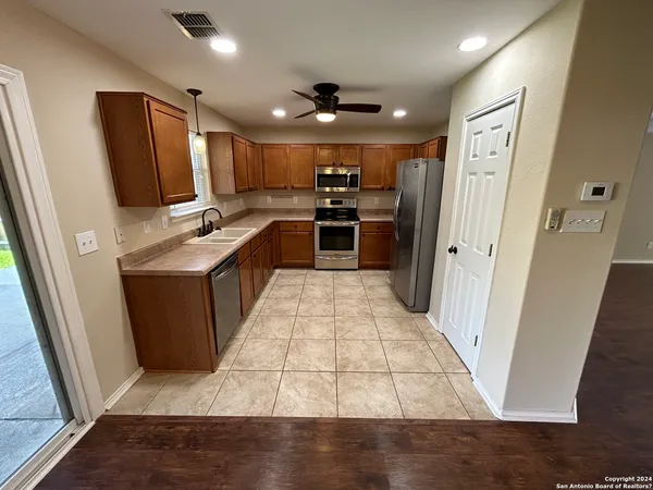 a large kitchen with a large counter top a refrigerator and cabinets
