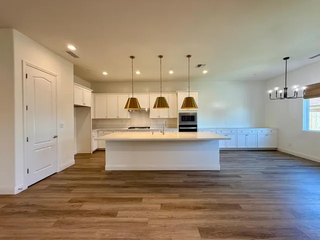 a view of a kitchen with kitchen island a sink stainless steel appliances and cabinets