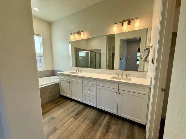 a bathroom with a double vanity sink mirror and bathtub