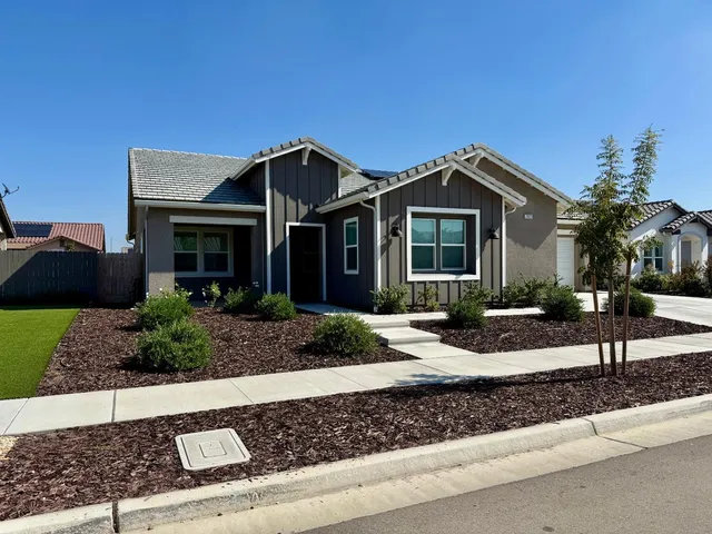 a front view of a house with garage and plants