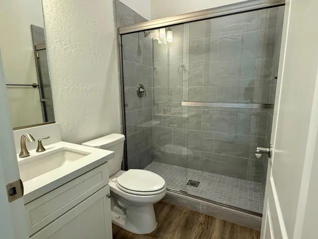 a bathroom with a shower sink vanity and toilet