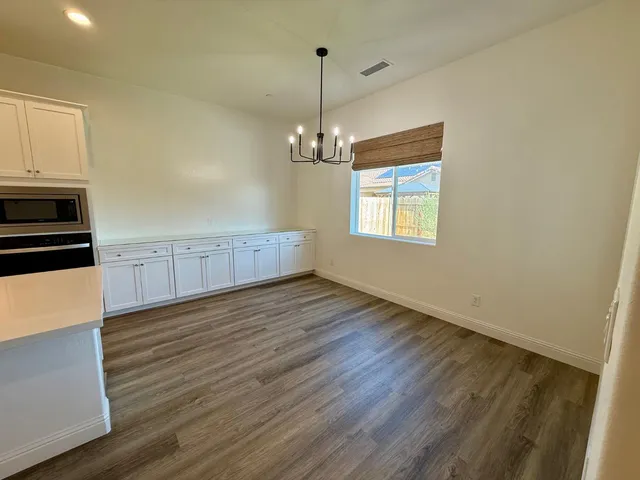 an empty room with wooden floor cabinet and windows