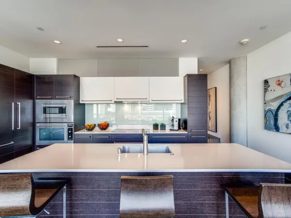 a room with stainless steel appliances kitchen island granite countertop a dining table and chairs