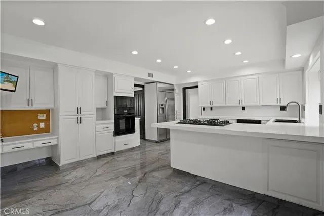 a large kitchen with stainless steel appliances a large counter top a stove and a refrigerator