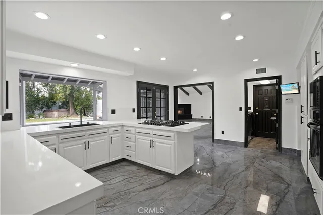 a large white kitchen with stainless steel appliances granite countertop a large counter top and a refrigerator