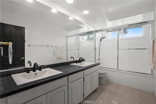 a bathroom with a sink double vanity granite tub shower and a mirror