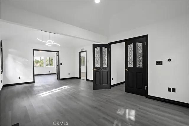 a view of an empty room with window and wooden floor